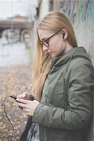 Young woman using smartphone by graffiti wall Stock Photo - Premium Royalty-Free, Code: 649-08125225