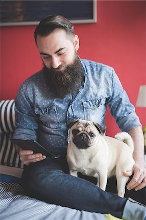 red shirt - Young bearded man using smartphone on bed Stock Photo - Premium Royalty-Free, Code: 649-08125267