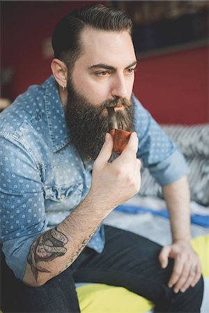 simsearch:649-08125285,k - Young bearded man smoking pipe on bed Photographie de stock - Premium Libres de Droits, Code: 649-08125278