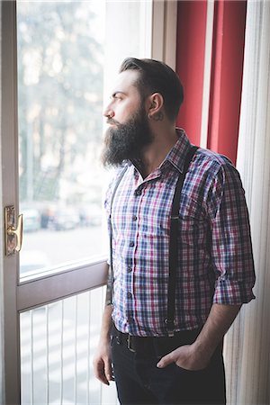 simsearch:649-08125288,k - Young bearded man in braces looking out of door Stock Photo - Premium Royalty-Free, Code: 649-08125287