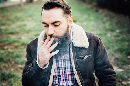 simsearch:649-08125306,k - Young bearded man smoking in park Stockbilder - Premium RF Lizenzfrei, Bildnummer: 649-08125301