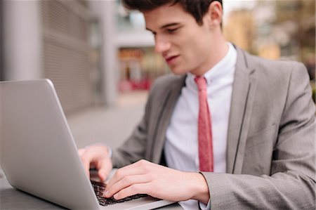 simsearch:649-08180101,k - Young city businessman typing on laptop at sidewalk cafe Fotografie stock - Premium Royalty-Free, Codice: 649-08125480