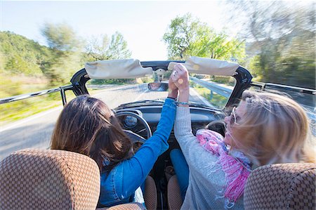 Two mature women, holding hands, in convertible car, rear view Fotografie stock - Premium Royalty-Free, Codice: 649-08125539