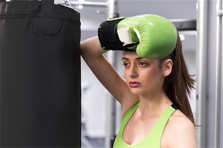 simsearch:649-08714043,k - Portrait of a young woman at gym leaning against punchbag wearing boxing glove Photographie de stock - Premium Libres de Droits, Code: 649-08125656