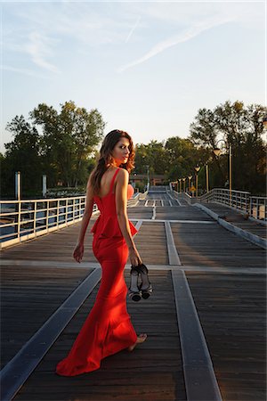 Portrait of a young woman in a smart red dress walking away and looking over shoulder Photographie de stock - Premium Libres de Droits, Code: 649-08125653