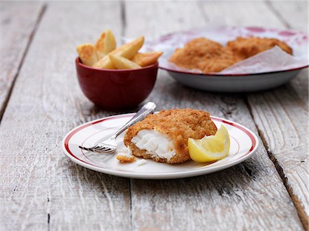 Breaded chunky cod with bowl of french fries on wooden table Stockbilder - Premium RF Lizenzfrei, Bildnummer: 649-08125691