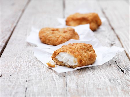 Three fried breaded chunky cod pieces on wooden table Fotografie stock - Premium Royalty-Free, Codice: 649-08125692