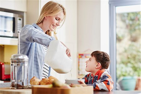 Mother pouring milk into son's breakfast bowl Foto de stock - Sin royalties Premium, Código: 649-08125787