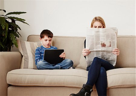 desconectar - Young boy using digital tablet, mother reading newspaper Foto de stock - Royalty Free Premium, Número: 649-08125805