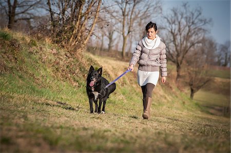 simsearch:614-08081252,k - Mid adult woman walking her dog in field Fotografie stock - Premium Royalty-Free, Codice: 649-08125924