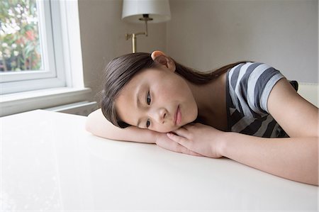 sleepy girl is sad - Unhappy girl at table resting on arms Stock Photo - Premium Royalty-Free, Code: 649-08125964