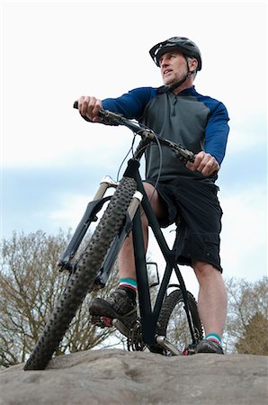 sporting male 50 - Low angle view of mature male mountain biker looking out from rock formation Stock Photo - Premium Royalty-Free, Code: 649-08125986