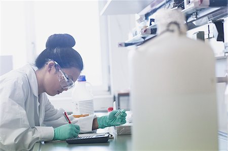 drugs results - Young female scientist making research notes on lab workbench Stock Photo - Premium Royalty-Free, Code: 649-08126034