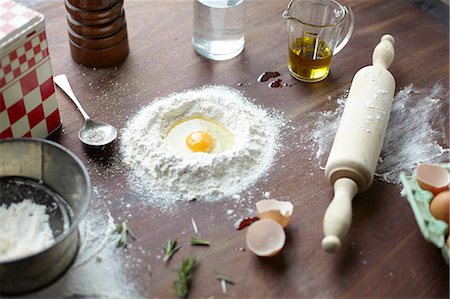 Table with raw egg in center of flour stack and kitchen utensils Photographie de stock - Premium Libres de Droits, Code: 649-08144228