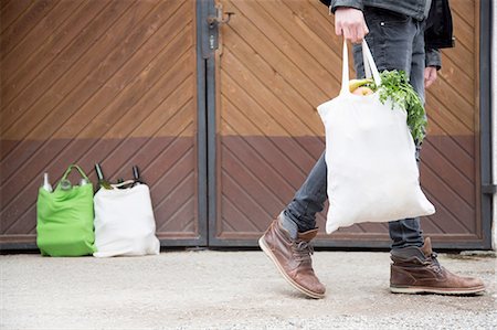 disposal - Teenage boy carrying reusable shopping bag full of fruit and veg, with bottles for recycling in yard Stock Photo - Premium Royalty-Free, Code: 649-08144283