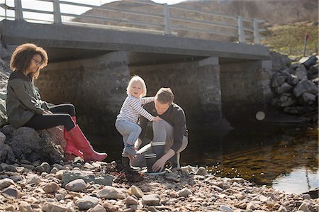 rubber boots family - Father putting wellingtons on son by footbridge Stock Photo - Premium Royalty-Free, Code: 649-08144419