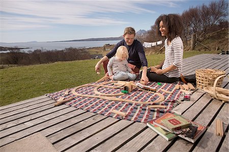 Boy and parents playing with toy train on wooden decking Stock Photo - Premium Royalty-Free, Code: 649-08144467