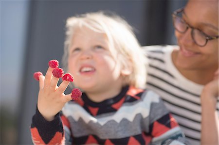 raspberry fingers - Boy with raspberries on fingers, mother watching Stock Photo - Premium Royalty-Free, Code: 649-08144584