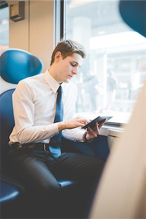 people sitting in a train - Portrait of young businessman commuter using digital tablet on train. Stock Photo - Premium Royalty-Free, Code: 649-08144795