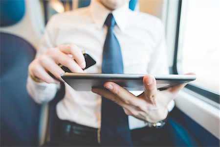 person tablet train - Portrait of young businessman commuter using digital tablet on train. Stock Photo - Premium Royalty-Free, Code: 649-08144796