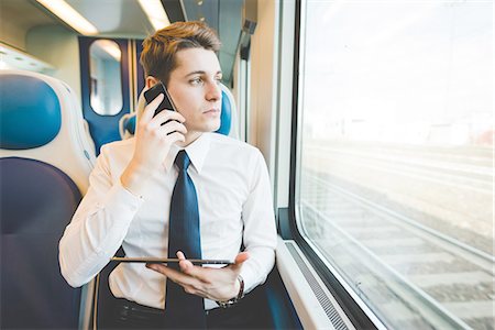 Portrait of young businessman commuter using digital tablet on train. Foto de stock - Sin royalties Premium, Código: 649-08144797