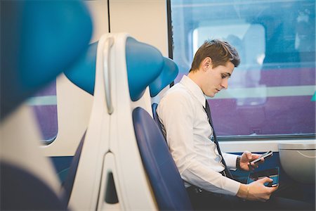 Portrait of young businessman commuter using digital tablet on train. Stock Photo - Premium Royalty-Free, Code: 649-08144792