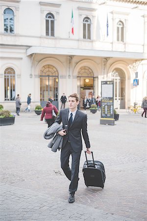 simsearch:649-08144823,k - Young businessman commuter walking along cobbled street with suitcase. Photographie de stock - Premium Libres de Droits, Code: 649-08144801