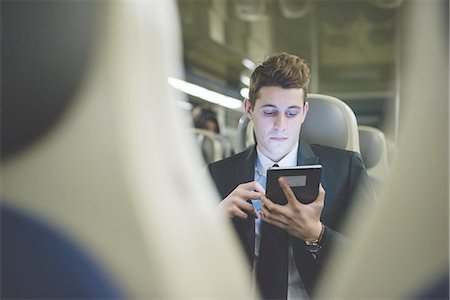 people commuting on trains - Portrait of young businessman commuter using digital tablet on train. Stock Photo - Premium Royalty-Free, Code: 649-08144814