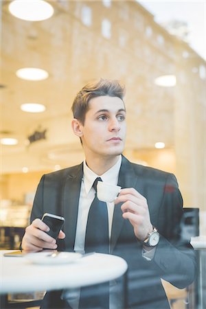 Portrait of young businessman sitting in cafe using digital tablet and mobile phone. Stock Photo - Premium Royalty-Free, Code: 649-08144824