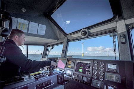 Captain of boat steering through offshore wind farm Stock Photo - Premium Royalty-Free, Code: 649-08145124