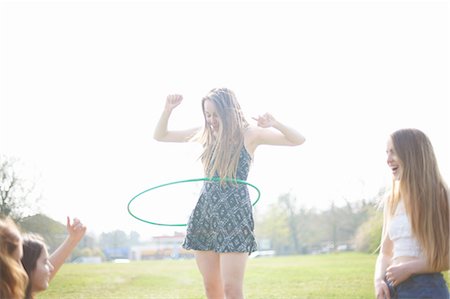 Teenage girl hoola hooping for friends in park Stock Photo - Premium Royalty-Free, Code: 649-08145149