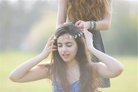 simsearch:649-08145149,k - Two teenage girls putting on and wearing daisy chain headdresses in park Foto de stock - Royalty Free Premium, Número: 649-08145169