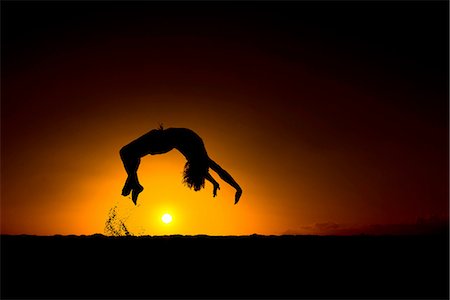 Silhouette of man doing back flip, at sunset, Omakaha, Oahu, Hawaii Fotografie stock - Premium Royalty-Free, Codice: 649-08145266