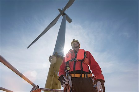 environmental issues - Engineer preparing to climb windturbine at offshore windfarm, low angle view Stock Photo - Premium Royalty-Free, Code: 649-08145387