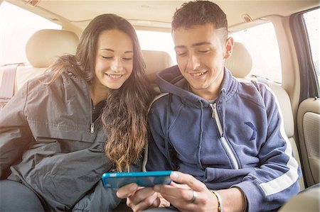 siblings - Teenage girl and young man reading smartphone text in car back seat Stock Photo - Premium Royalty-Free, Code: 649-08145564