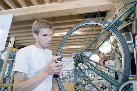 Mid adult man in workshop lubricating bicycle wheel Stock Photo - Premium Royalty-Free, Code: 649-08145579