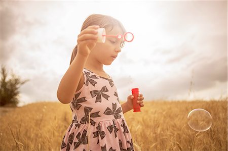 Girl blowing bubbles in wheat field Stock Photo - Premium Royalty-Free, Code: 649-08179891