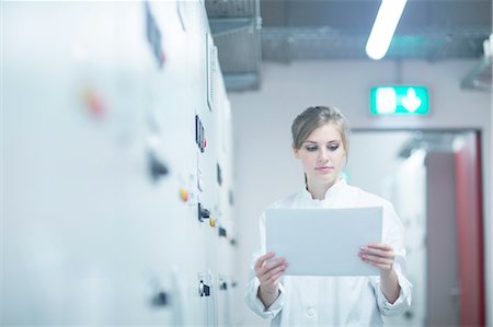 Young female scientist reading paperwork in technical room Photographie de stock - Premium Libres de Droits, Code: 649-08180011