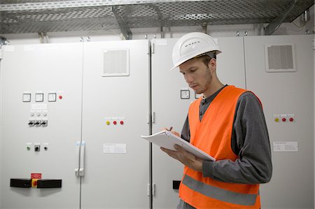 engineer at industry control room - Young male engineer reading paperwork in technical room Stock Photo - Premium Royalty-Free, Code: 649-08180026