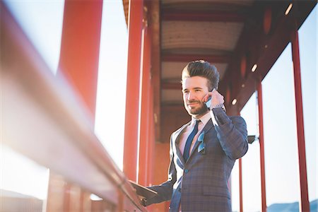 simsearch:649-08180101,k - Young man with digital tablet chatting on smartphone on footbridge Fotografie stock - Premium Royalty-Free, Codice: 649-08180098