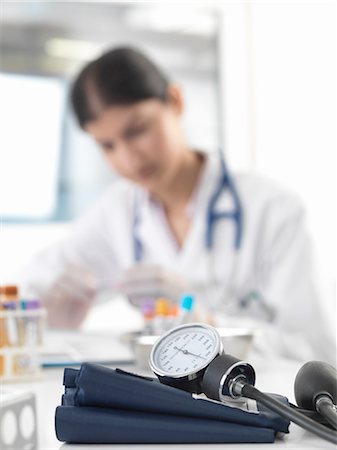 doctor with test tube - Female doctor examining test tube at desk in clinic Stock Photo - Premium Royalty-Free, Code: 649-08180348