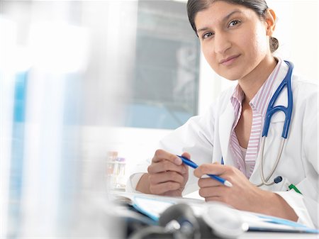 simsearch:649-08086430,k - Portrait of female doctor at desk working on medical records Foto de stock - Sin royalties Premium, Código: 649-08180354