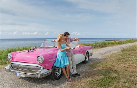 simsearch:649-08180382,k - Young couple looking at map beside vintage convertible at coast, Havana, Cuba Photographie de stock - Premium Libres de Droits, Code: 649-08180370