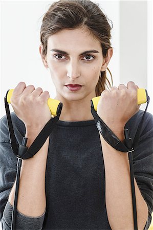 Close up of young woman exercising with resistance bands in living room Stock Photo - Premium Royalty-Free, Code: 649-08180458