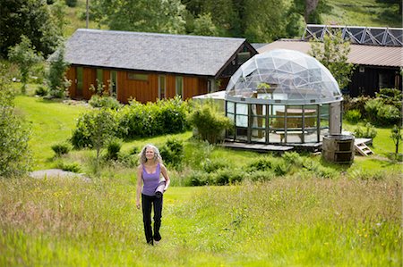 simsearch:649-08180502,k - Mature woman carrying yoga mat walking up eco lodge field Foto de stock - Sin royalties Premium, Código: 649-08180483