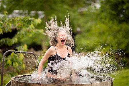 Mature woman splashing into fresh cold water tub at eco retreat Stock Photo - Premium Royalty-Free, Code: 649-08180540