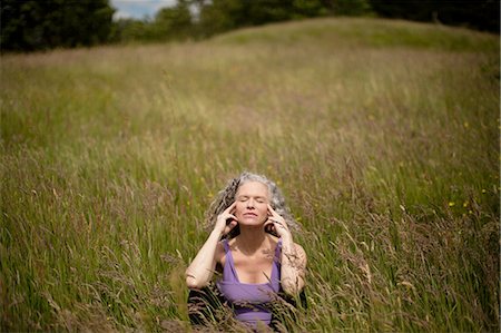 simsearch:649-08180502,k - Mature woman with fingers on her temples sitting in long grass meditating Foto de stock - Sin royalties Premium, Código: 649-08180553