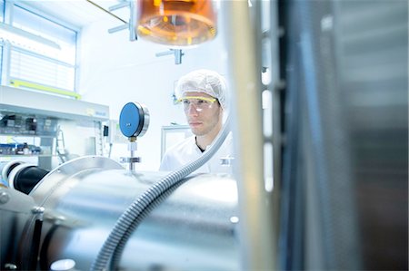 simsearch:649-07118833,k - Male scientist reading equipment gauge in lab cleanroom Foto de stock - Sin royalties Premium, Código: 649-08180600