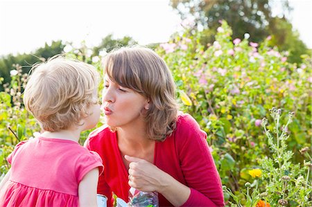 pucker - Mid adult mother and toddler daughter kissing in flower field Foto de stock - Sin royalties Premium, Código: 649-08180671