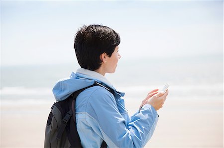 simsearch:649-08949538,k - Mid adult woman texting on smartphone from beach whilst looking out to sea Photographie de stock - Premium Libres de Droits, Code: 649-08180684